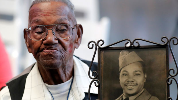 FILE - World War II veteran Lawrence Brooks holds a photo of him taken in 1943, as he celebrates his 110th birthday at the National World War II Museum in New Orleans, on Sept. 12, 2019. For Veterans Day, a group of Democratic lawmakers is reviving an effort to pay the families of Black servicemen who fought on behalf of the nation during World War II for benefits they were denied or prevented from taking full advantage of when they returned home from war. (AP Photo/Gerald Herbert, File)