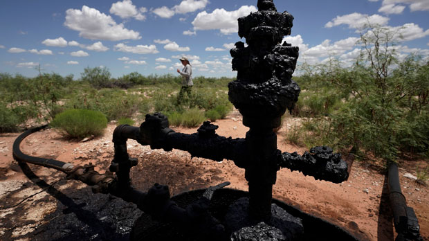 FILE - Ashley Williams Watt walks near a wellhead and flowline at her ranch, Friday, July 9, 2021, near Crane, Texas. The wells on Watt's property seem to be unplugging themselves. Some are leaking dangerous chemicals into the ground, which are seeping into her cattle's drinking water. And she doesn't know how long it's been going on. (AP Photo/Eric Gay, File)