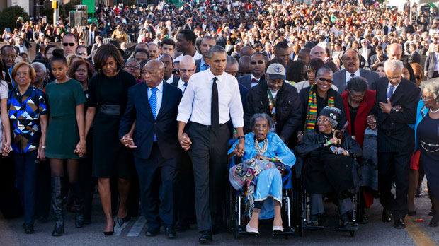 President Barack Obama, center, walks as he holds hands with Amelia Boynton Robinson