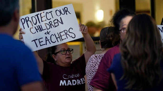 Parents and family of students hold protest signs during a special meeting of the Board of Trustees of Uvalde Consolidated Independent School District where parents addressed the shootings at Robb Elementary School, Monday, July 18, 2022, in Uvalde, Texas. (AP Photo/Eric Gay)