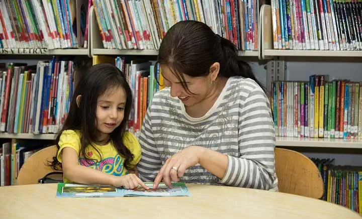 "Parent & Children reading a book" Photo Courtesy of: Literacy Partners.