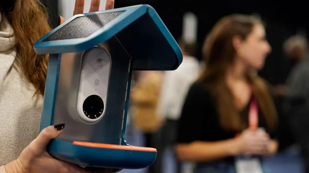 An exhibitor holds up the Bird Buddy smart camera bird feeder