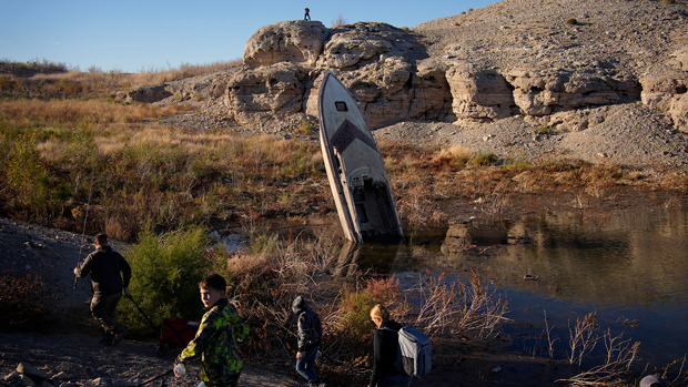 People walk by a formerly sunken boat standing upright